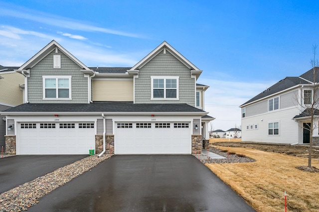 view of front of property with stone siding, an attached garage, and driveway