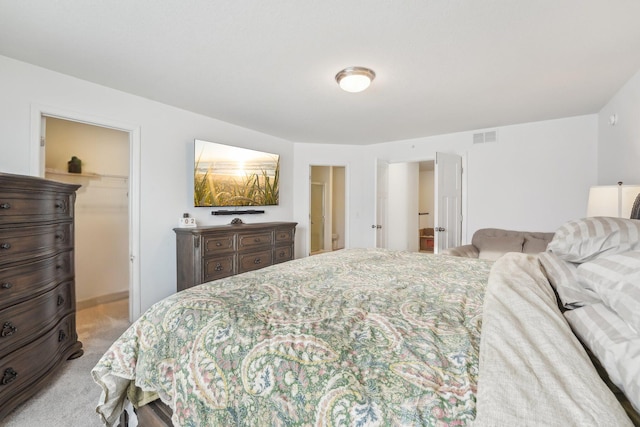 bedroom featuring a closet, visible vents, a walk in closet, and carpet flooring