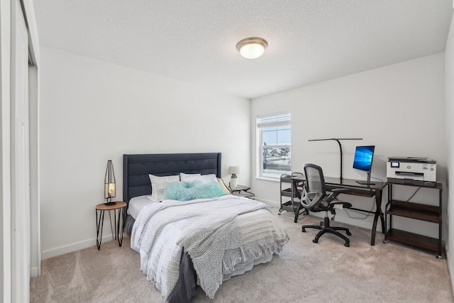 carpeted bedroom with a textured ceiling and baseboards