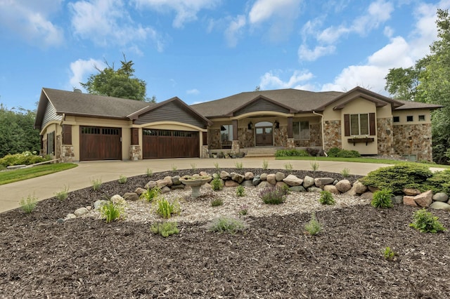 view of front of house with a garage, stone siding, concrete driveway, and french doors