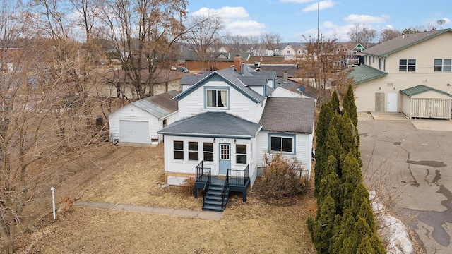 traditional-style home with an outbuilding, roof with shingles, a garage, a residential view, and driveway