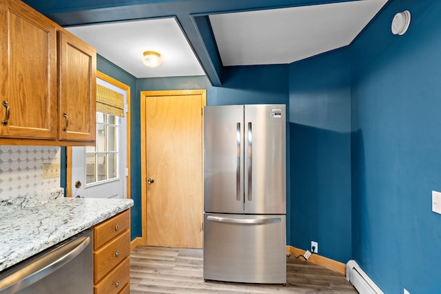 kitchen with appliances with stainless steel finishes, a baseboard radiator, light wood-style floors, and baseboards