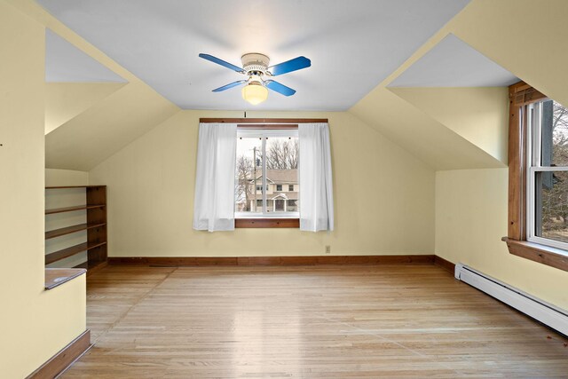 additional living space featuring a baseboard radiator, baseboards, vaulted ceiling, and wood finished floors