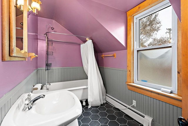 bathroom featuring wainscoting, lofted ceiling, shower / bath combo with shower curtain, baseboard heating, and a sink