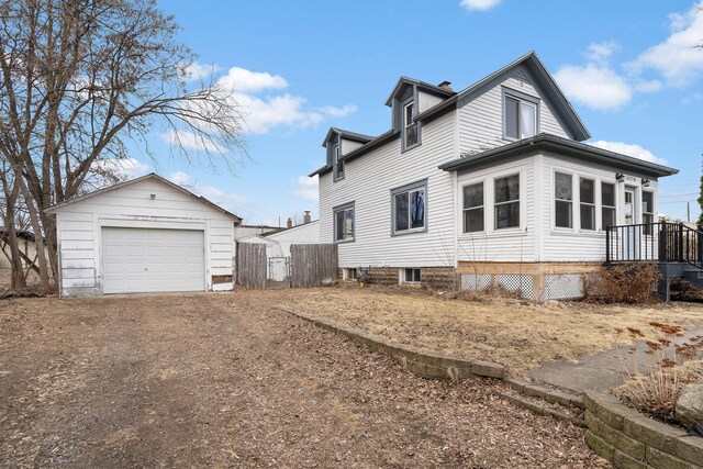 view of side of property with an outbuilding, driveway, a detached garage, and fence