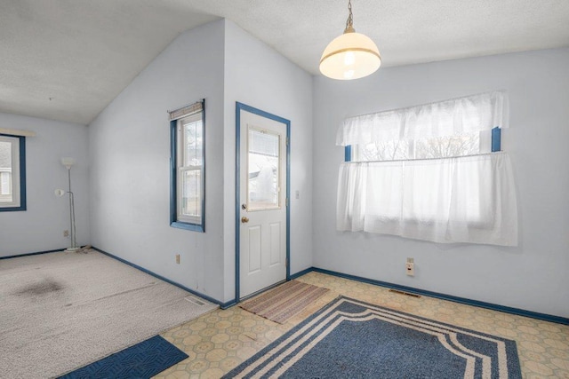 foyer entrance with lofted ceiling, visible vents, baseboards, and a textured ceiling