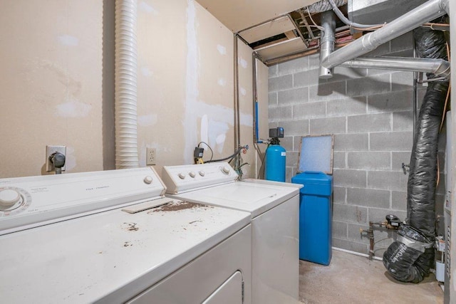 clothes washing area featuring laundry area, concrete block wall, and washing machine and clothes dryer