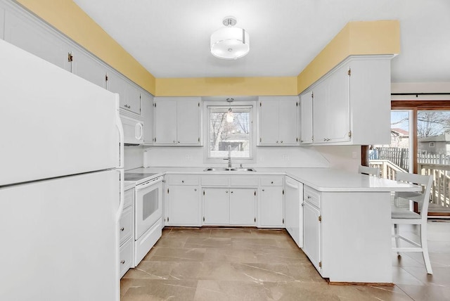 kitchen with a peninsula, white appliances, a sink, light countertops, and a kitchen bar