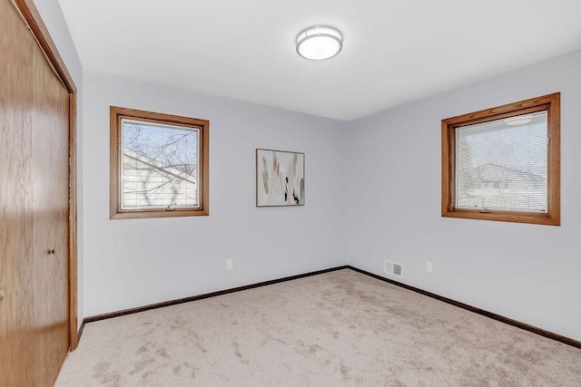 carpeted empty room featuring baseboards and visible vents