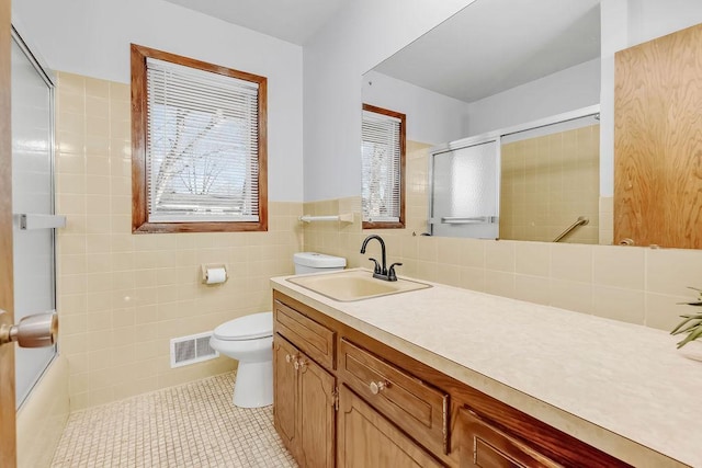 bathroom with tile walls, visible vents, toilet, vanity, and tile patterned floors