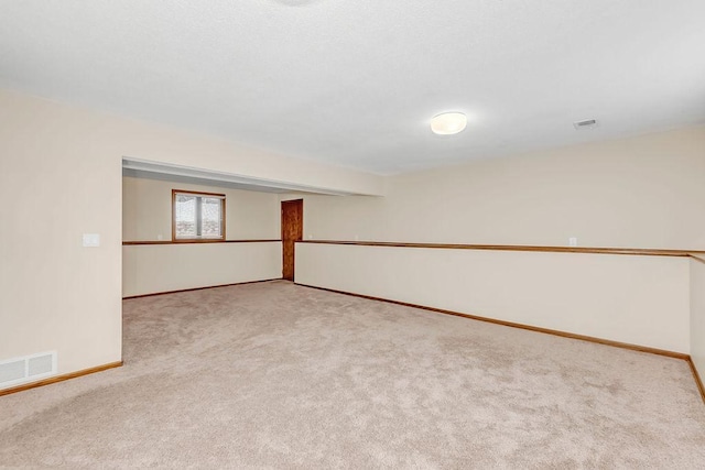 carpeted spare room with visible vents and baseboards