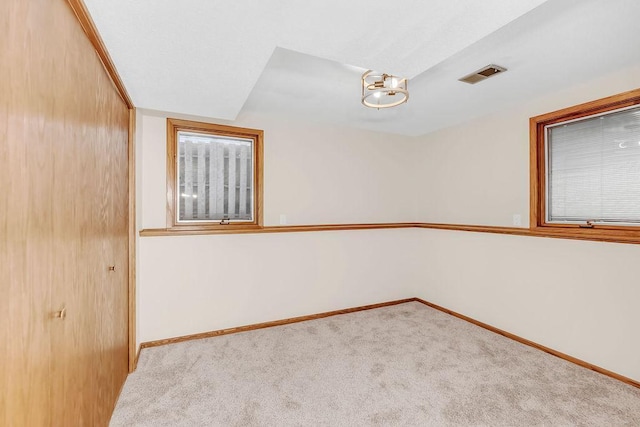 carpeted spare room featuring visible vents and baseboards