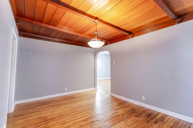 unfurnished room with beamed ceiling, baseboards, and arched walkways