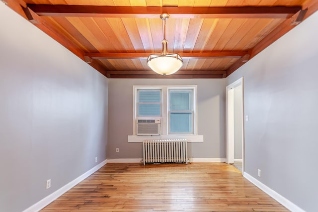 unfurnished room featuring hardwood / wood-style floors, beamed ceiling, radiator heating unit, and baseboards