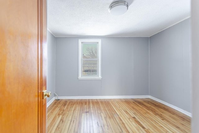 unfurnished room featuring baseboards, a textured ceiling, hardwood / wood-style floors, and crown molding