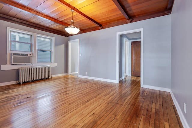 empty room featuring beamed ceiling, baseboards, radiator, and wood ceiling