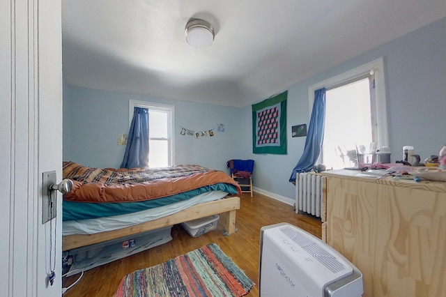 bedroom with baseboards, radiator, and wood finished floors