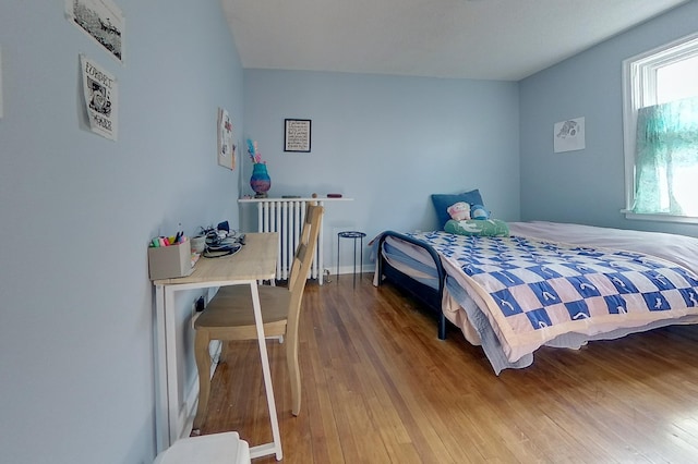 bedroom featuring baseboards, wood finished floors, and radiator heating unit