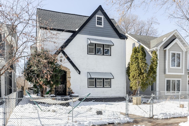 view of front of home with a fenced front yard, roof with shingles, stucco siding, and a gate