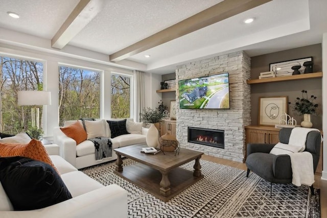 living area featuring wood finished floors, a textured ceiling, a fireplace, beam ceiling, and recessed lighting