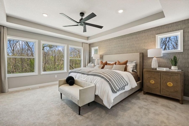 carpeted bedroom featuring a tray ceiling, ceiling fan, baseboards, and recessed lighting