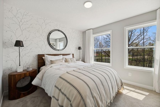 carpeted bedroom featuring multiple windows, baseboards, and wallpapered walls