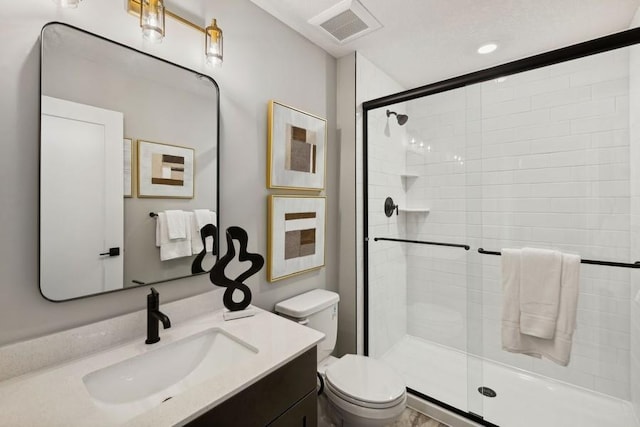 bathroom with toilet, a stall shower, vanity, and visible vents