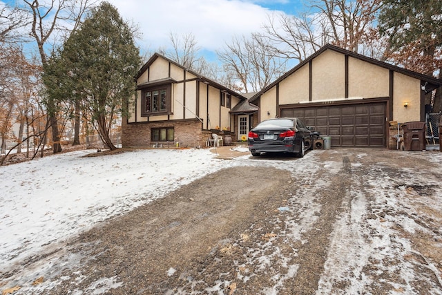 tudor-style house with brick siding, driveway, and stucco siding