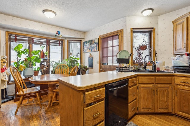 kitchen featuring light wood-type flooring, wallpapered walls, light countertops, and a textured ceiling