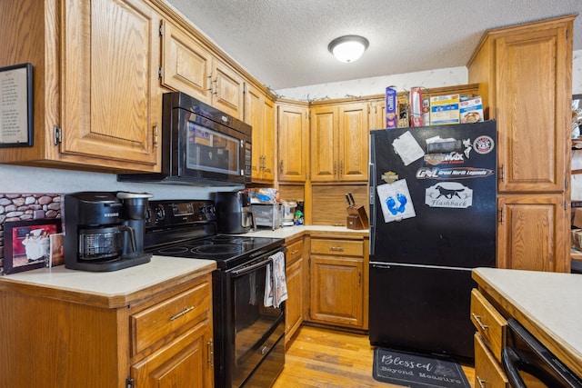 kitchen with light wood-style floors, light countertops, a textured ceiling, and black appliances