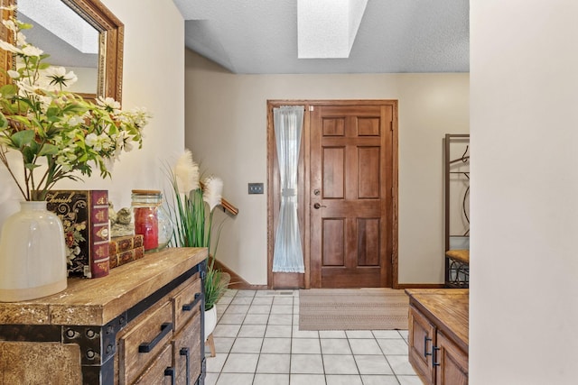 entryway with baseboards, light tile patterned flooring, and a skylight