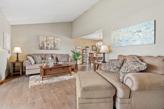 living area with an inviting chandelier, baseboards, light wood-style floors, and lofted ceiling