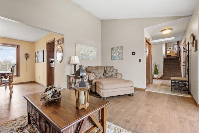 living area with stairway, baseboards, and light wood finished floors