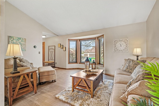 living room with baseboards, lofted ceiling, and light wood finished floors