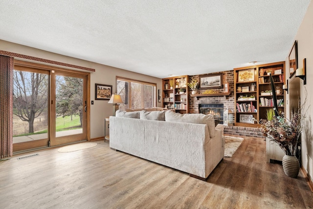 living room with visible vents, a textured ceiling, wood finished floors, and a fireplace