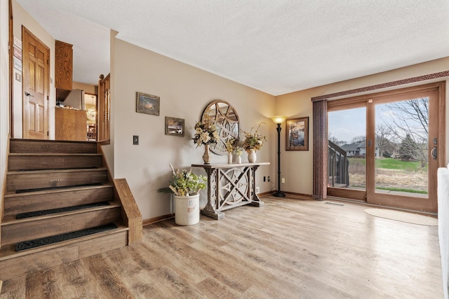 interior space with visible vents, stairs, wood finished floors, baseboards, and a textured ceiling
