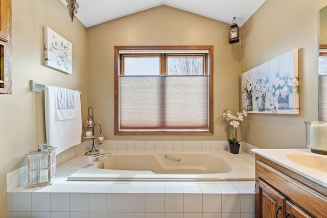 bathroom with vaulted ceiling, vanity, and a garden tub