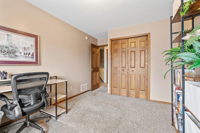 carpeted home office featuring a textured ceiling, visible vents, and baseboards