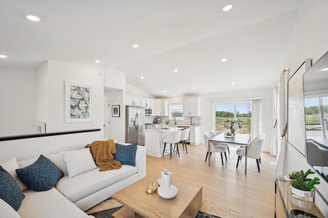 living area featuring vaulted ceiling, light wood finished floors, plenty of natural light, and recessed lighting