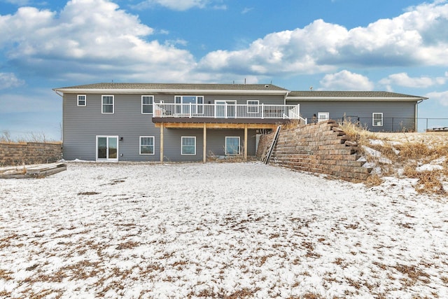 snow covered rear of property featuring stairway and a deck