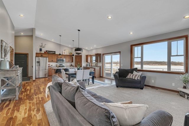 living area featuring recessed lighting, light wood-type flooring, baseboards, and high vaulted ceiling