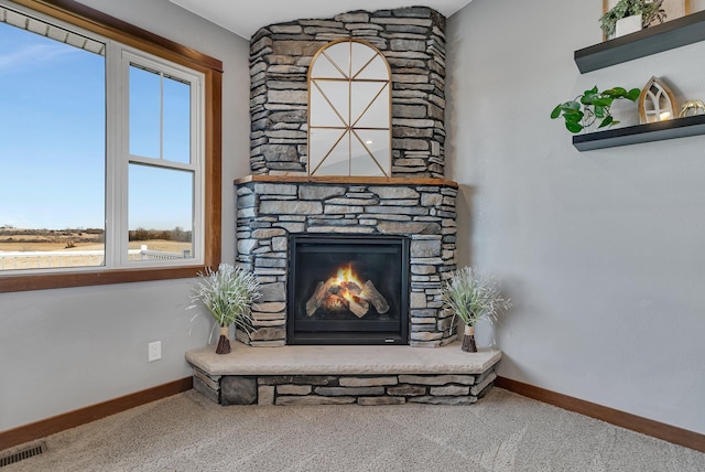 interior details with visible vents, a stone fireplace, baseboards, and carpet floors