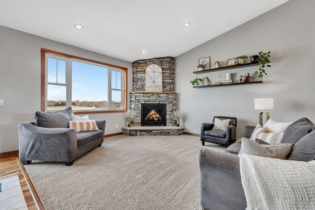 carpeted living area featuring a stone fireplace, vaulted ceiling, recessed lighting, and baseboards