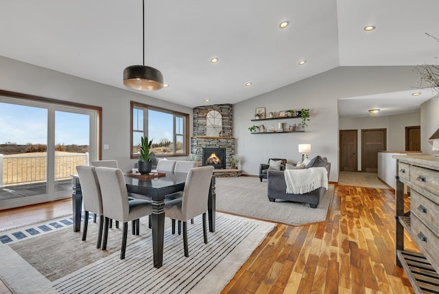 dining area featuring recessed lighting, light wood-style floors, a fireplace, baseboards, and vaulted ceiling