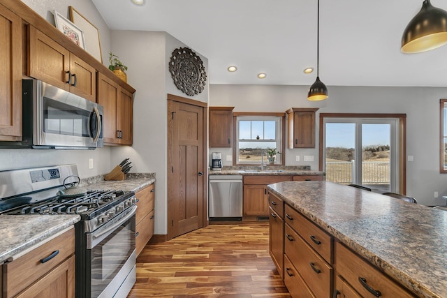 kitchen with brown cabinetry, light wood finished floors, recessed lighting, a sink, and appliances with stainless steel finishes