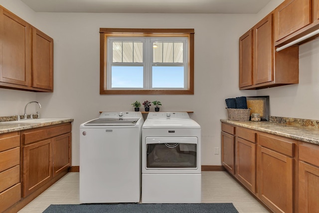 washroom with cabinet space, washer and dryer, baseboards, and a sink