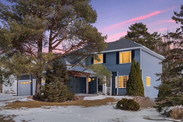 traditional home featuring an attached garage, a pergola, and roof with shingles