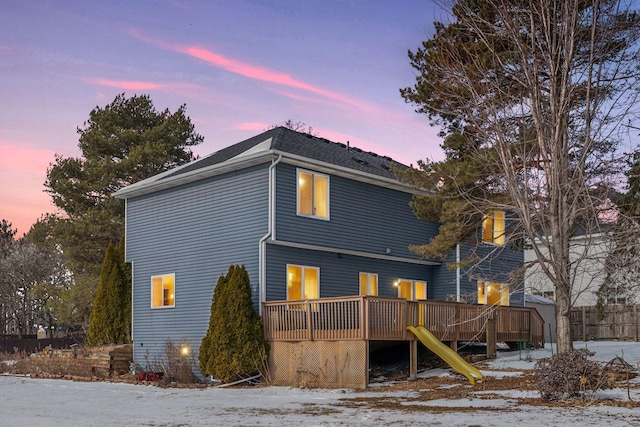 snow covered back of property with stairs and a wooden deck