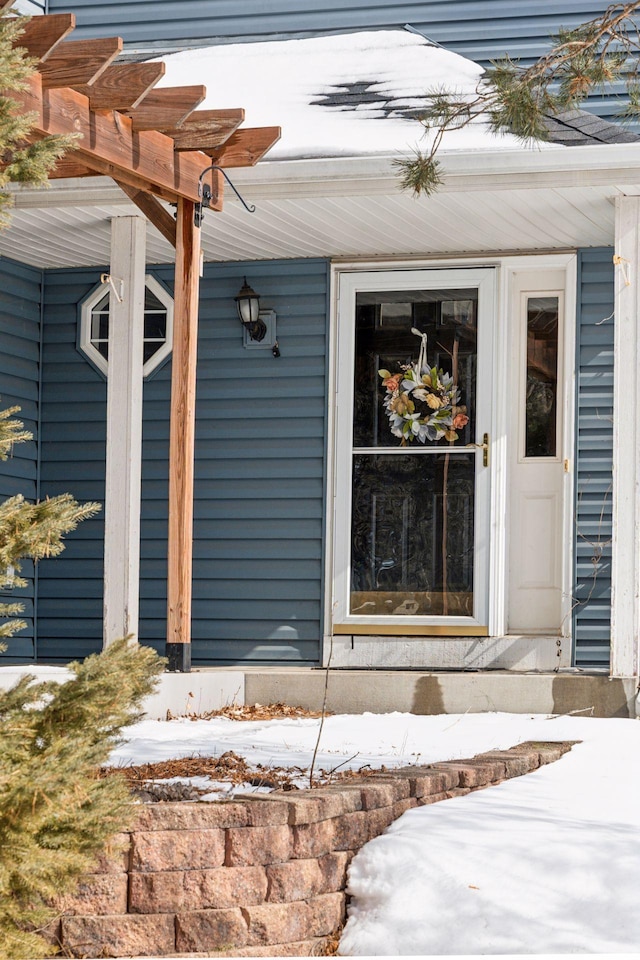 snow covered property entrance with a pergola