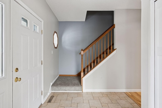 foyer entrance featuring stairway and baseboards